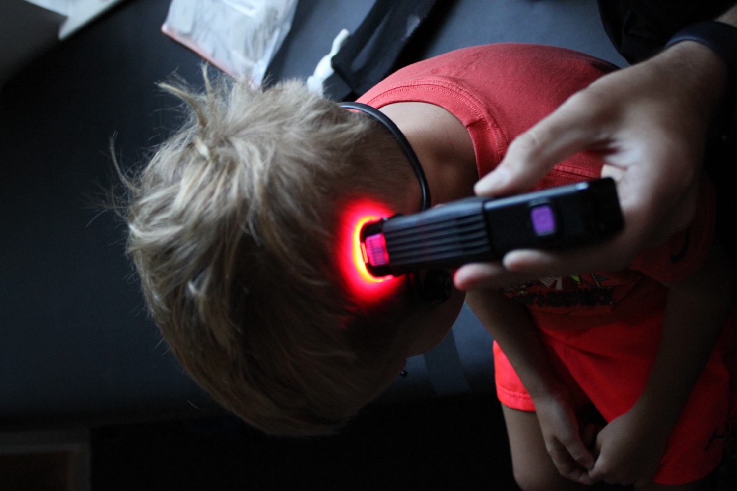 Close-up of a red low-level laser device being applied to a child's head during a calm photobiomodulation session